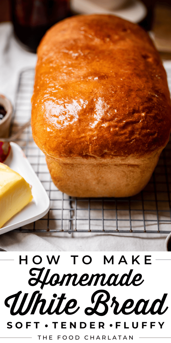 a whole loaf of uncut white bread out of the pan sitting on a cooling rack.
