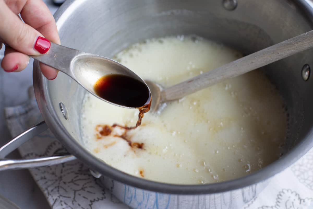 Adding vanilla to a pot of bubbly syrup.