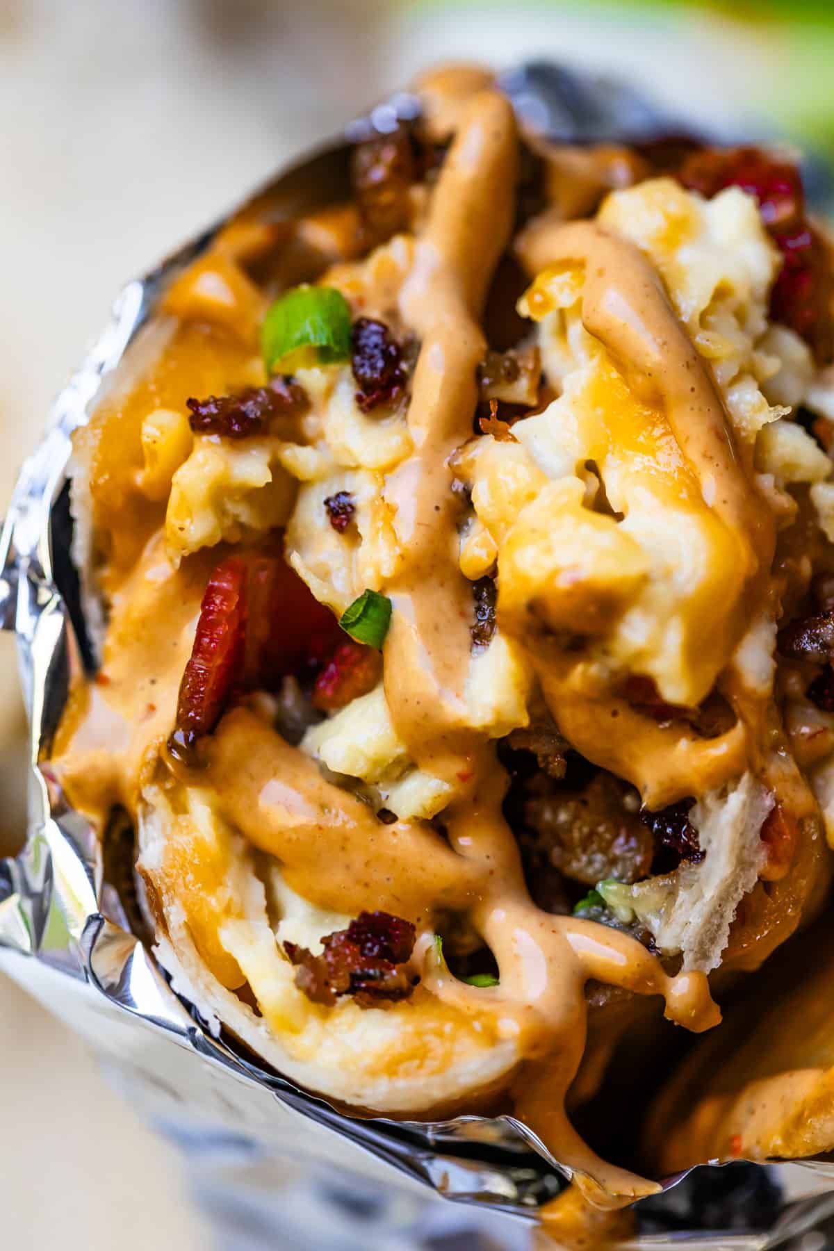 Close-up of breakfast burrito with chipotle mayo on top.