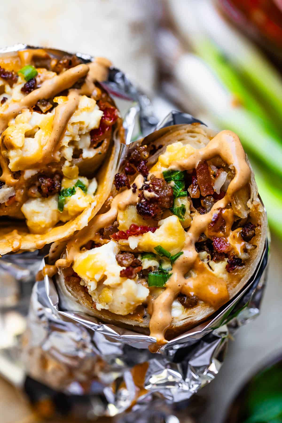 breakfast burritos wrapped in aluminum foil close up.