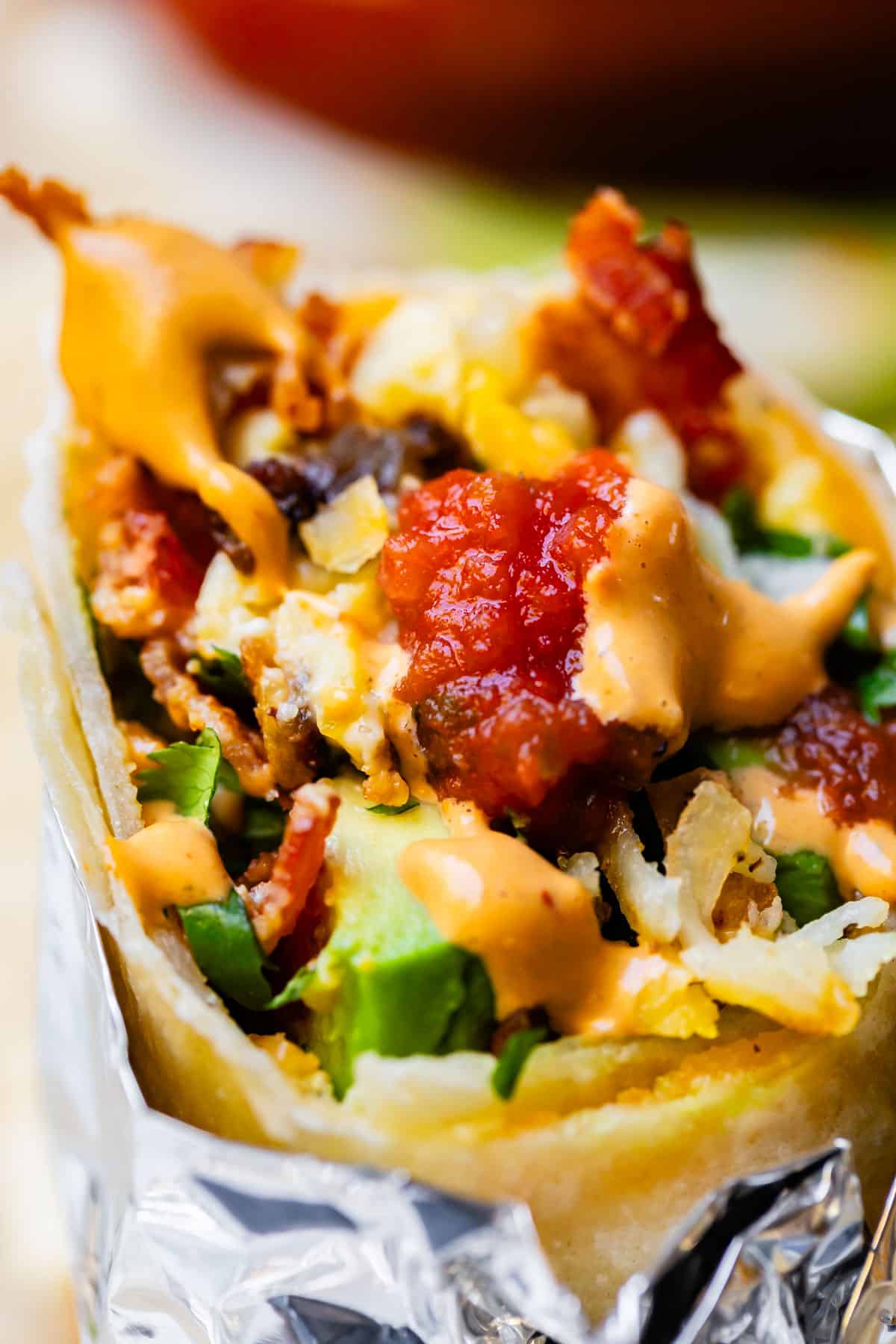 Breakfast burrito with bite out of it and salsa.