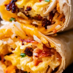 two breakfast burritos stacked on top of each other with cheese.