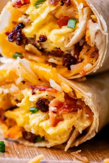 two breakfast burritos stacked on top of each other with cheese.