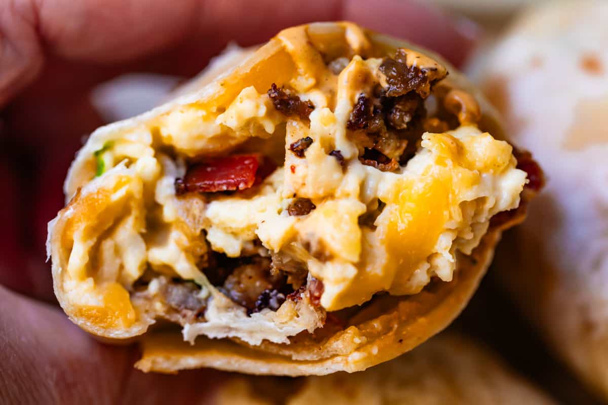 half of an egg and meat breakfast burrito. 