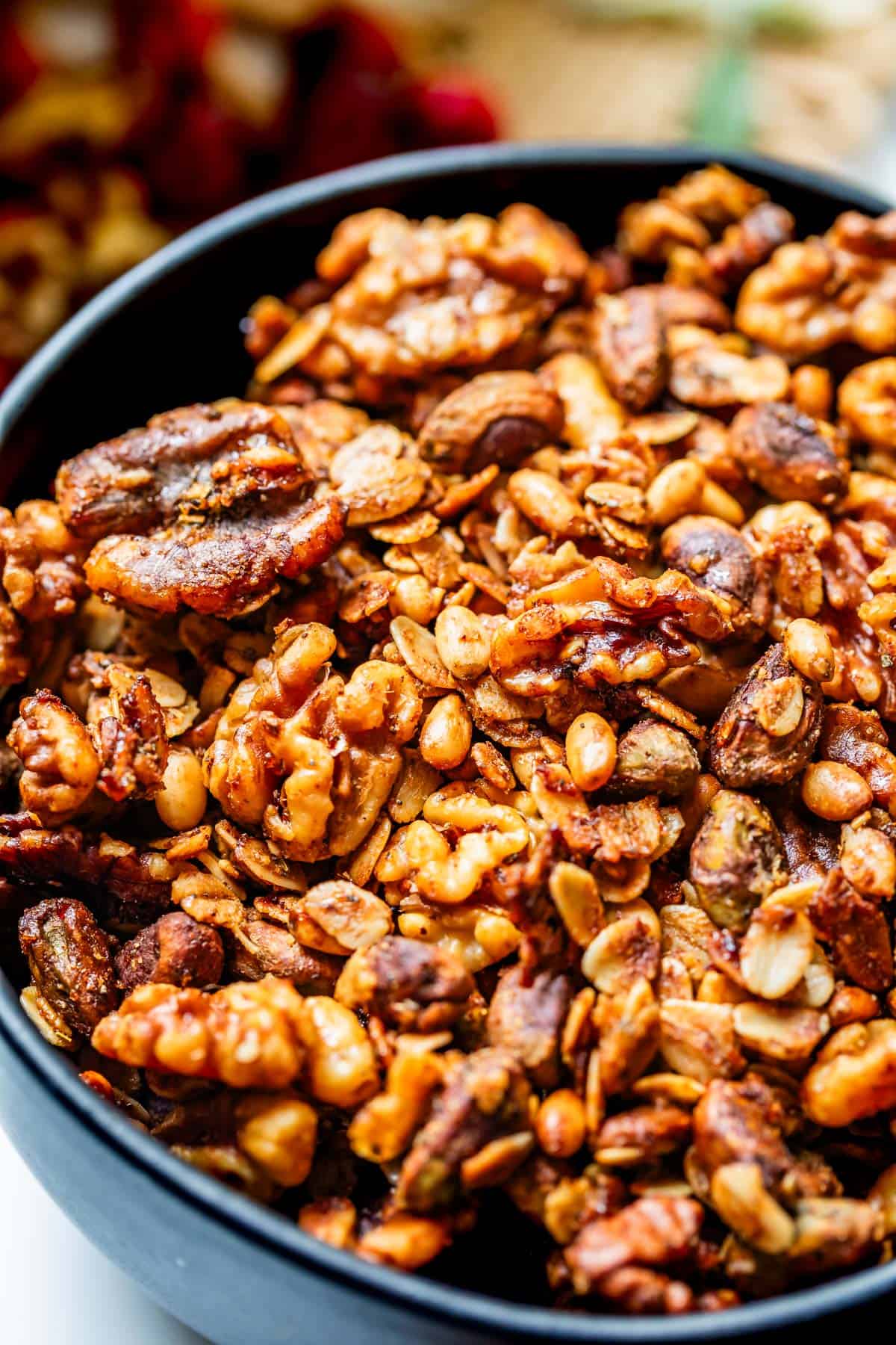 golden baked savory granola in a black ceramic bowl on a countertop.