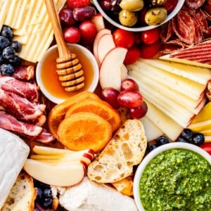 overhead charcuterie board ideas with oranges, apples, honey, pesto.