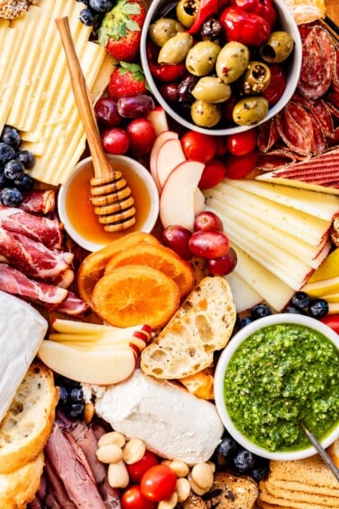 overhead charcuterie board ideas with oranges, apples, honey, pesto.