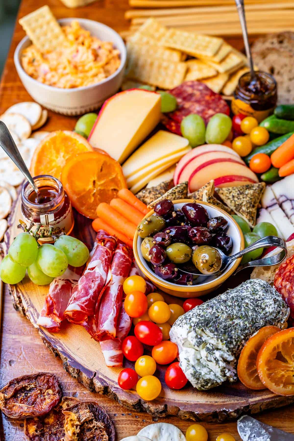 food on a wooden board ready to eat, like meats, cheese, carrots, jam, etc.