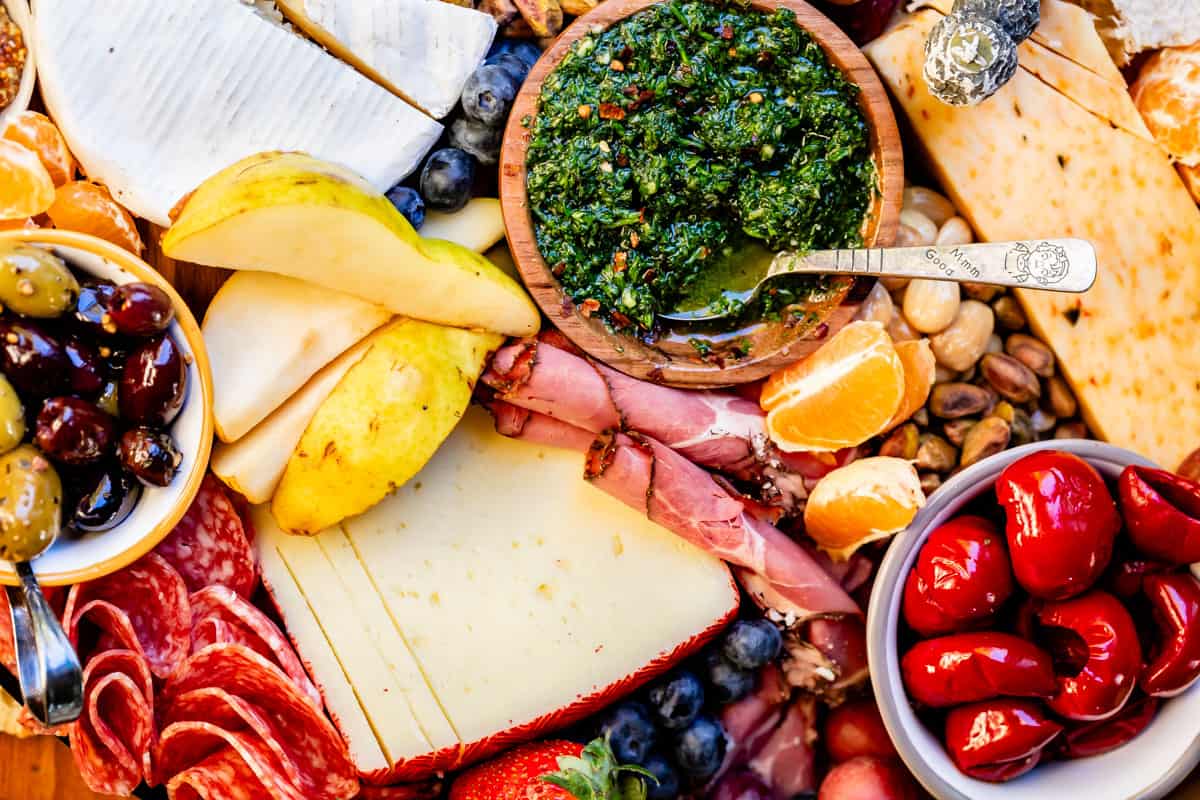 pears, chimichurri, mandarin, peppers, and cheese on a charcuterie board.