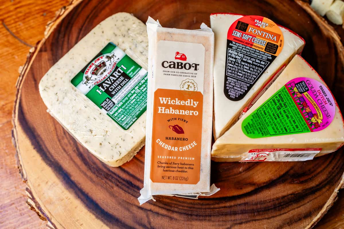 Arrangement of semi-soft packaged cheeses including havarti with dill, habañero cheddar, fontina, and gouda.