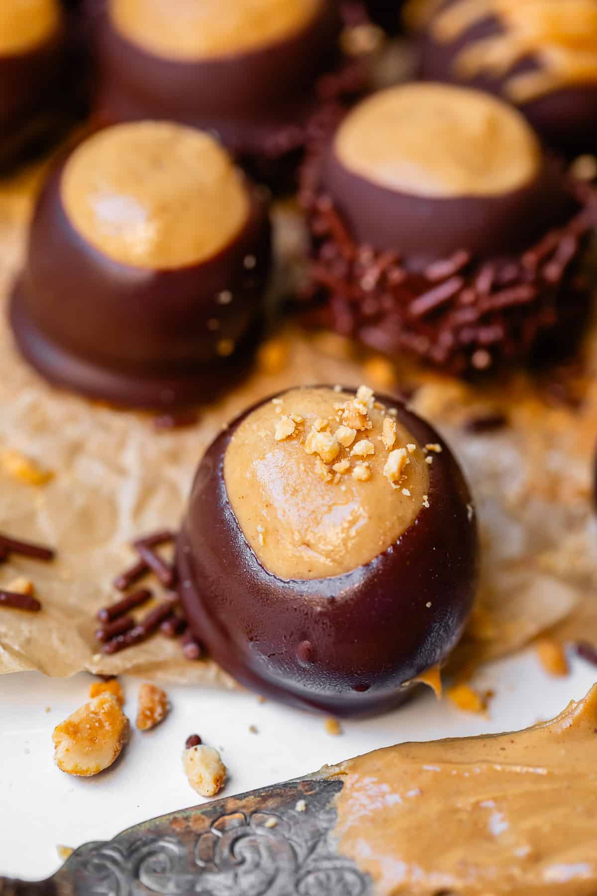 a buckeye candy recipe with nuts sprinkled on top on parchment paper.