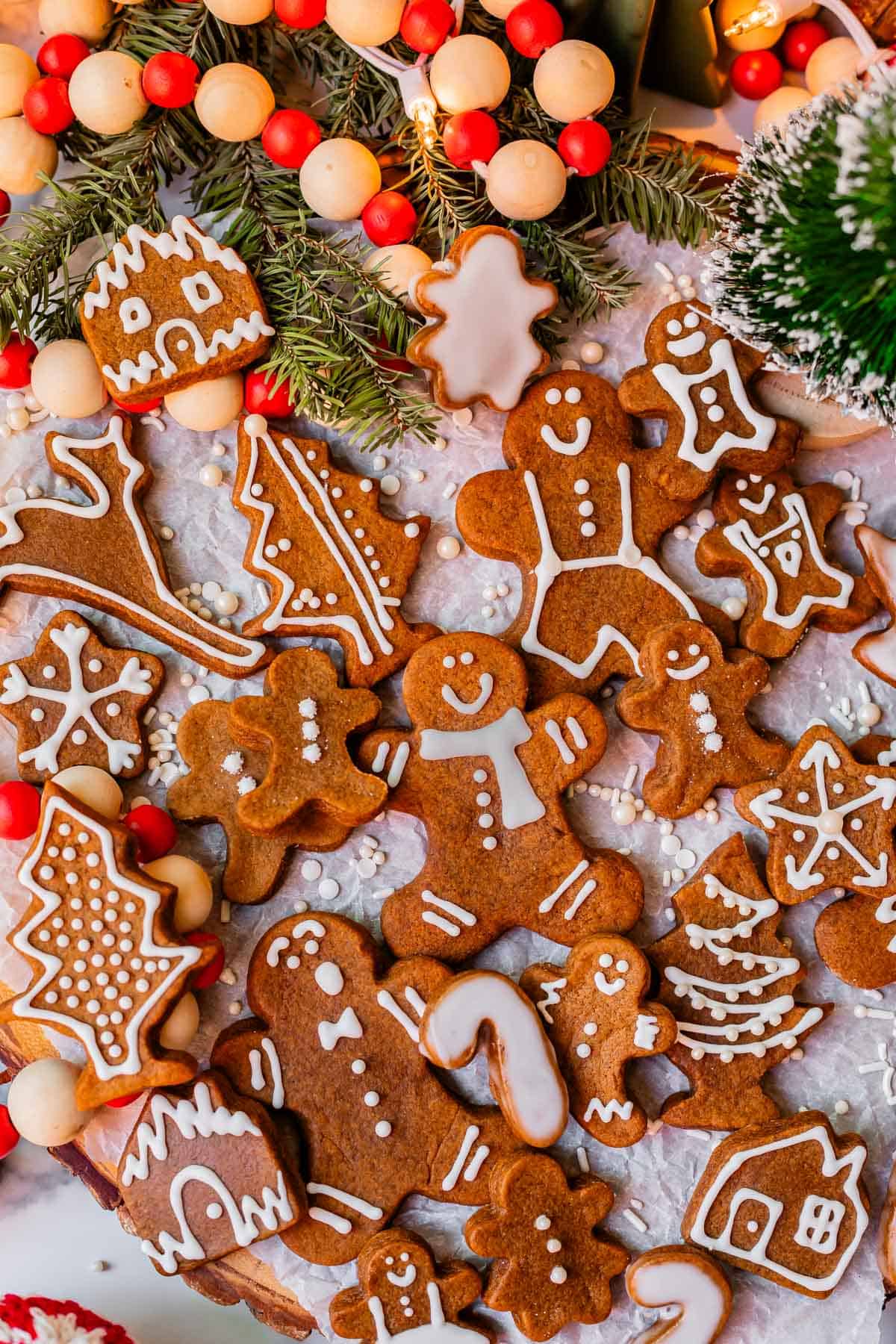 several dozen gingerbread man coookies with white icing lined up on white parchment paper.