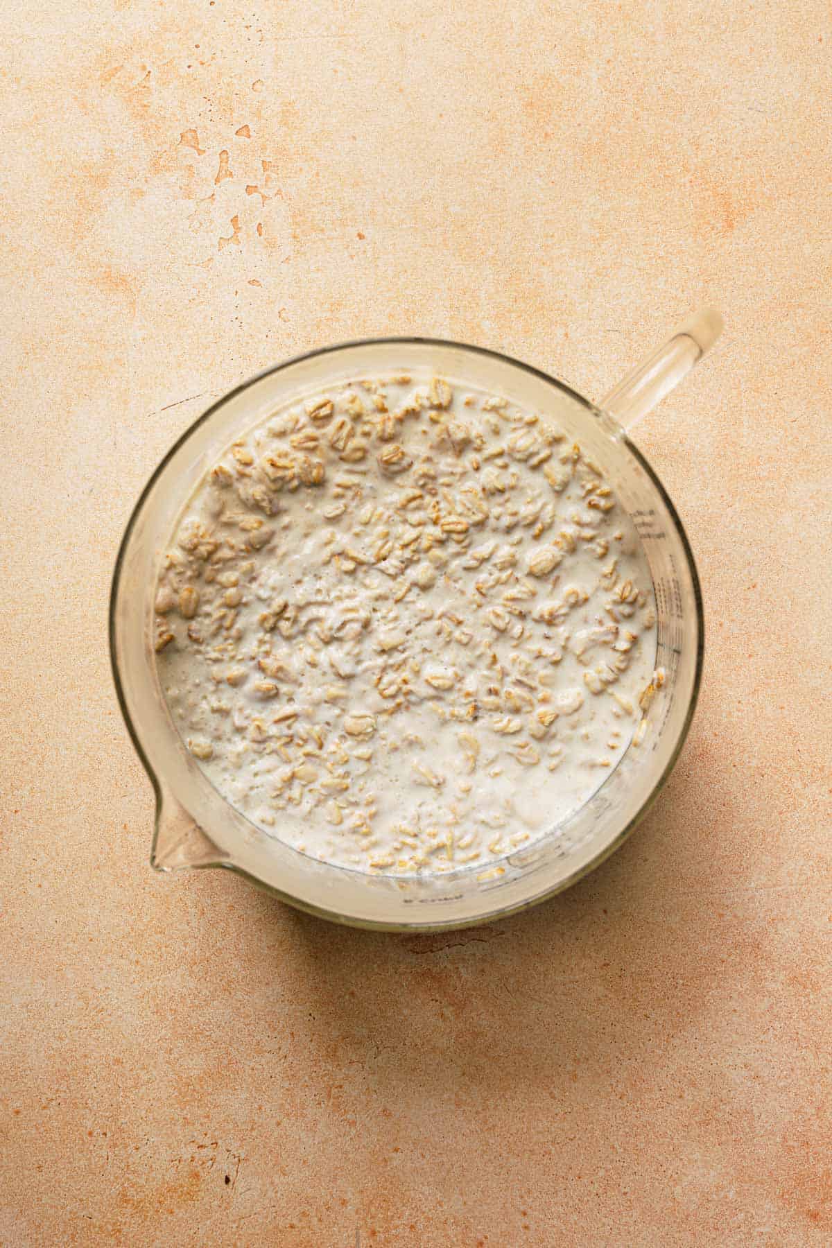 Oats soaked in buttermilk in large glass measuring bowl.