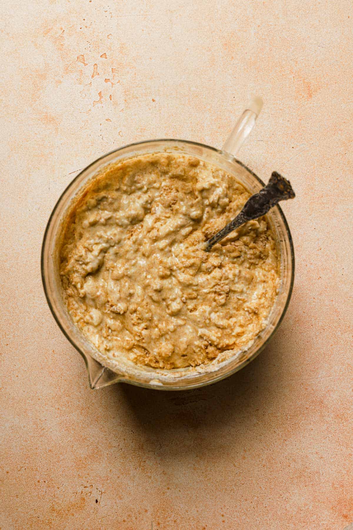 Mixed oatmeal pancake batter in large glass measuring bowl.
