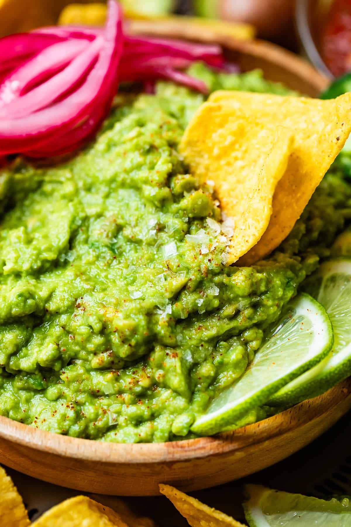 two chips together being used to scoop homemade guacamole out of the serving bowl.