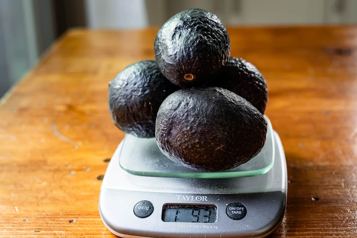 four avocados being weighed on a food scale to get the most accurate amount of ingredients.
