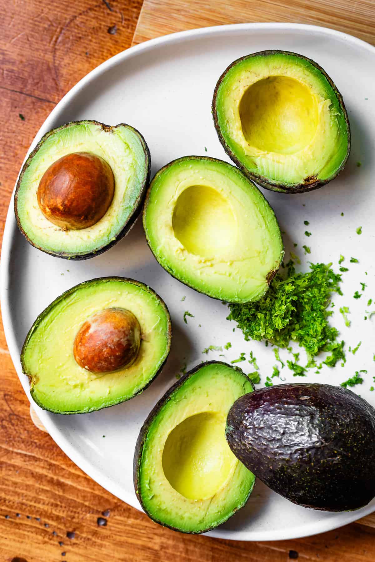 several avocado halves and lime zest resting on a plate.