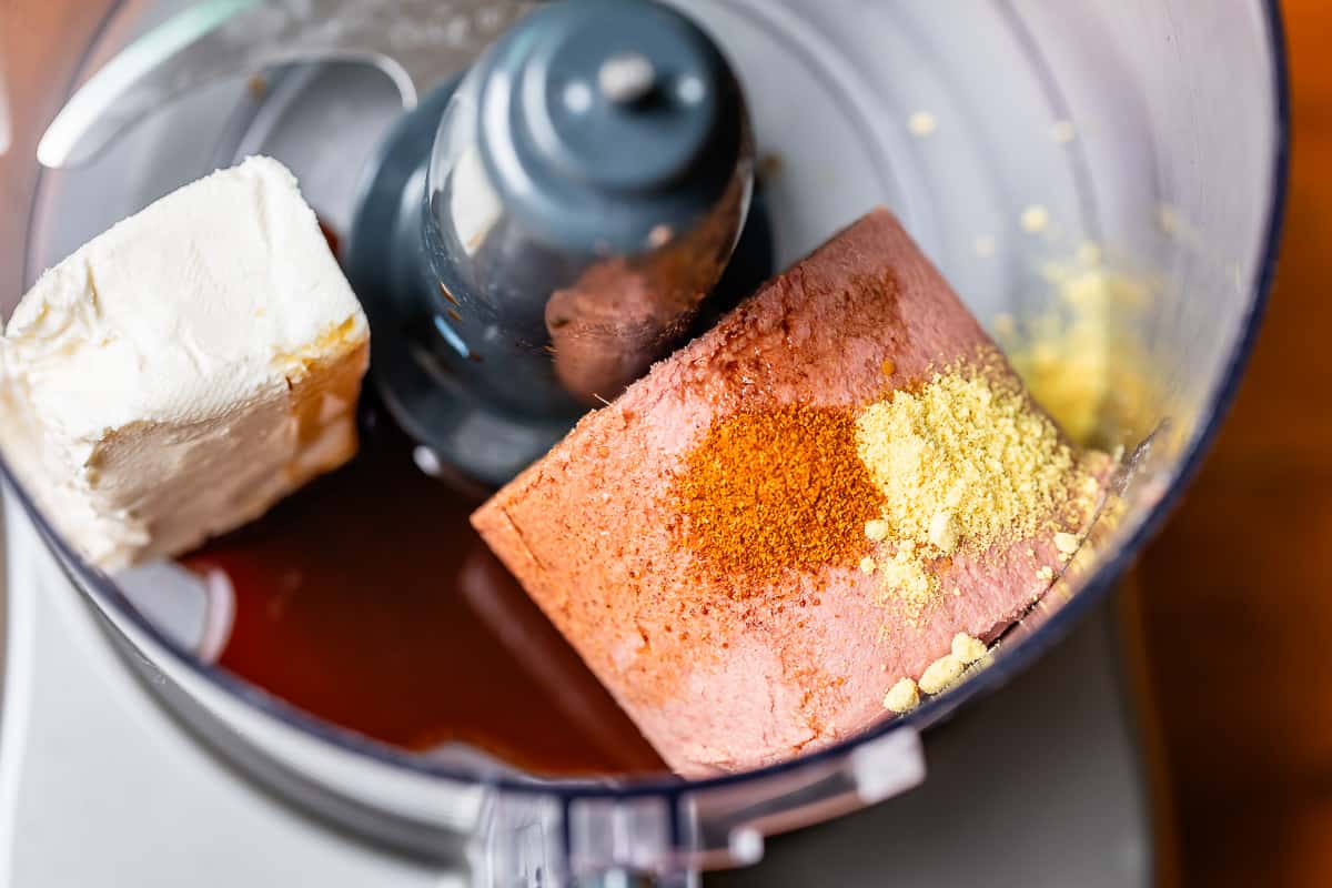 Braunschweiger, cream cheese, mustard powder, cayenne pepper, and worcestershire sauce in a food processor being being blended.