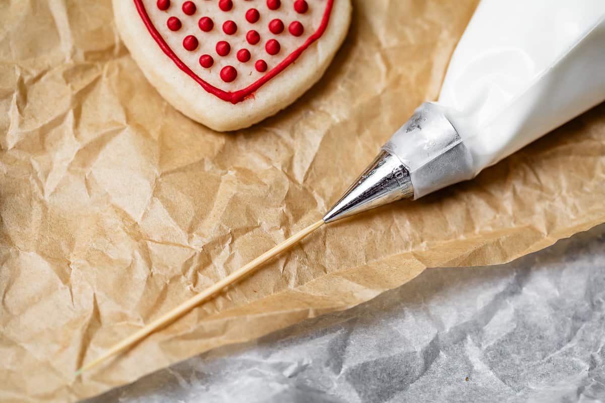 close up of a toothpick inserted into a piping tip to get it unclogged.