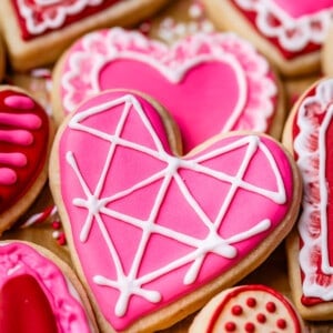 heart shaped sugar cookie with pink royal icing and white details.