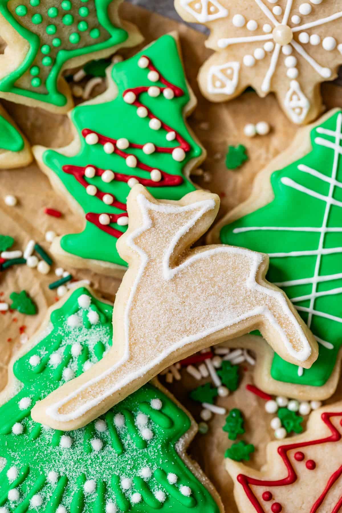 Reindeer sugar cookie with outline done in white royal icing on top of assortment of Christmas sugar cookies.