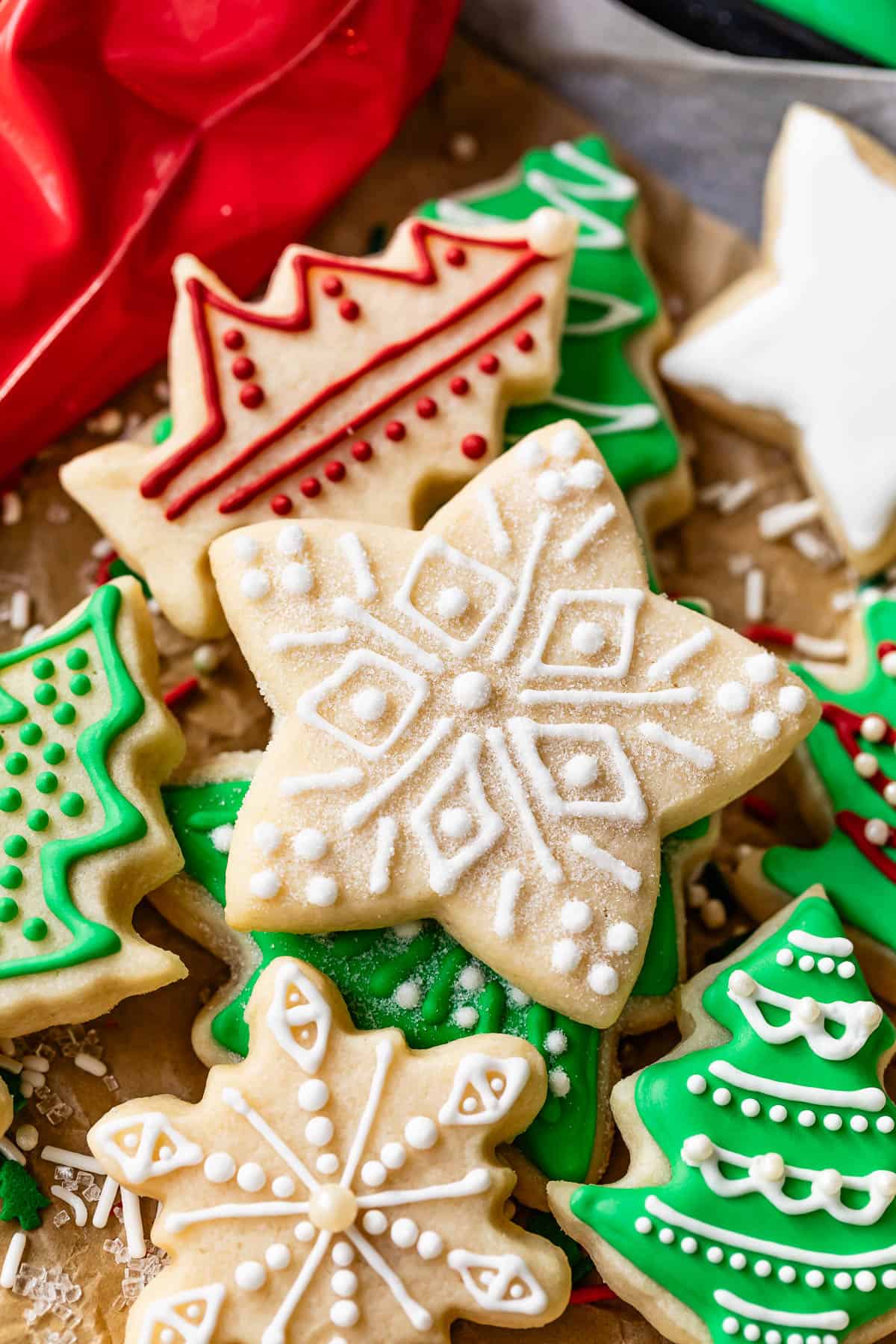 Star sugar cookie with royal icing design and sugar decoration on top of pile of other Christmas cookies.