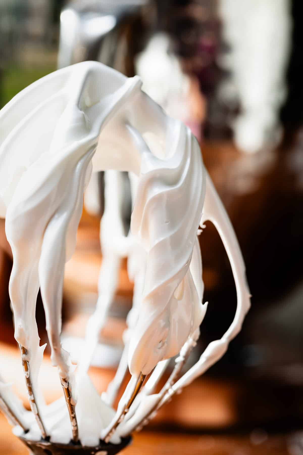 upside down whisk showing icing that is just thicker than toothpaste.