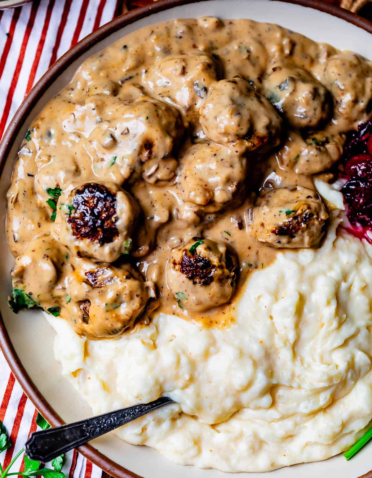 a plate half filled with mashed potatoes the other half with swedish meatballs and gravy.