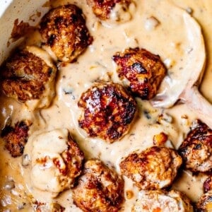 looking down into a skillet filled with creamy brown gravy, and swedish meatballs.