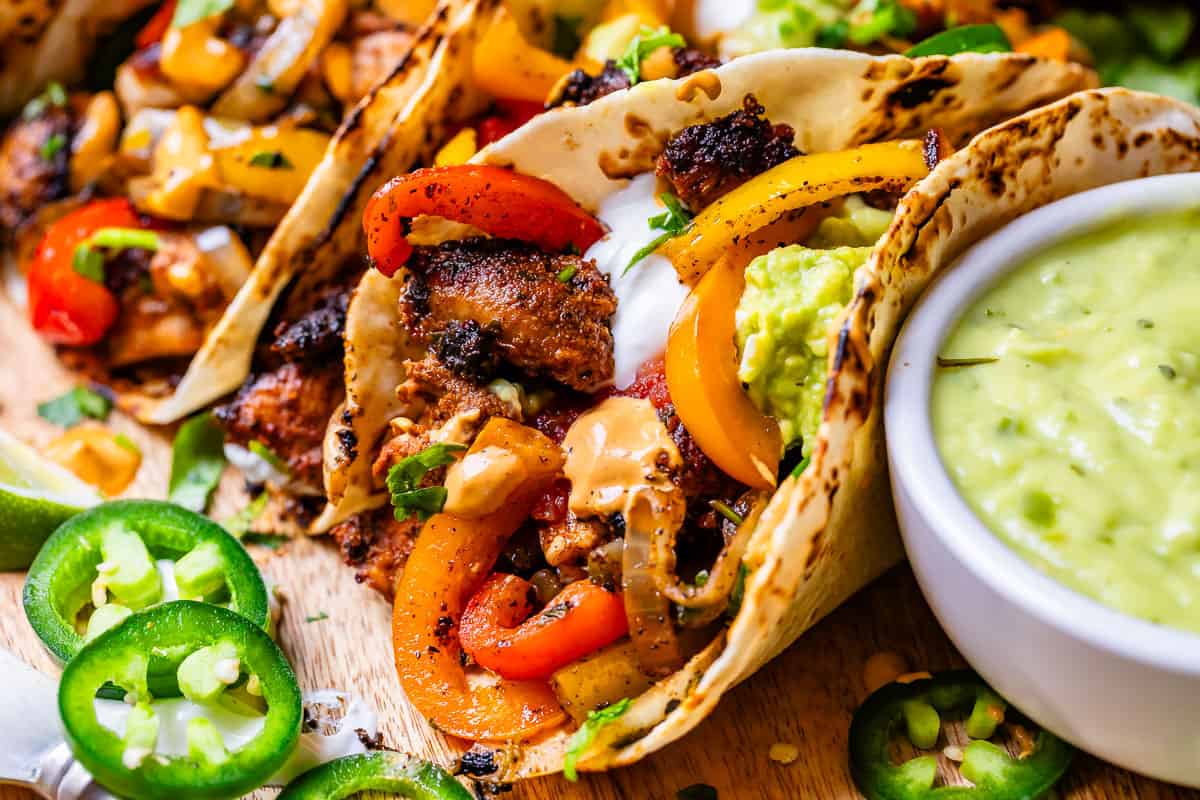 a filled chicken fajita next to a bowl with creamy tomatillo jalapeno sauce for dipping.