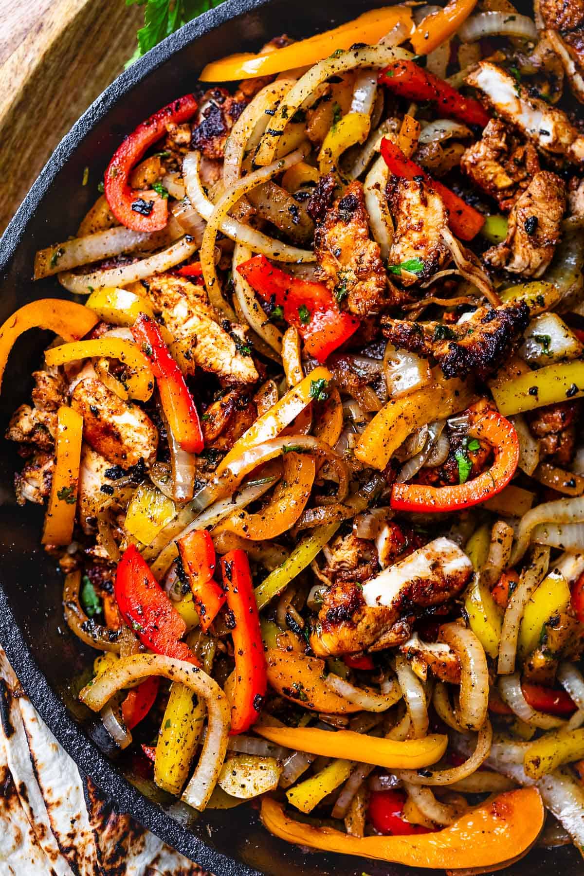 looking down at a cast iron skillet filled with blackened chicken, onions, and peppers.