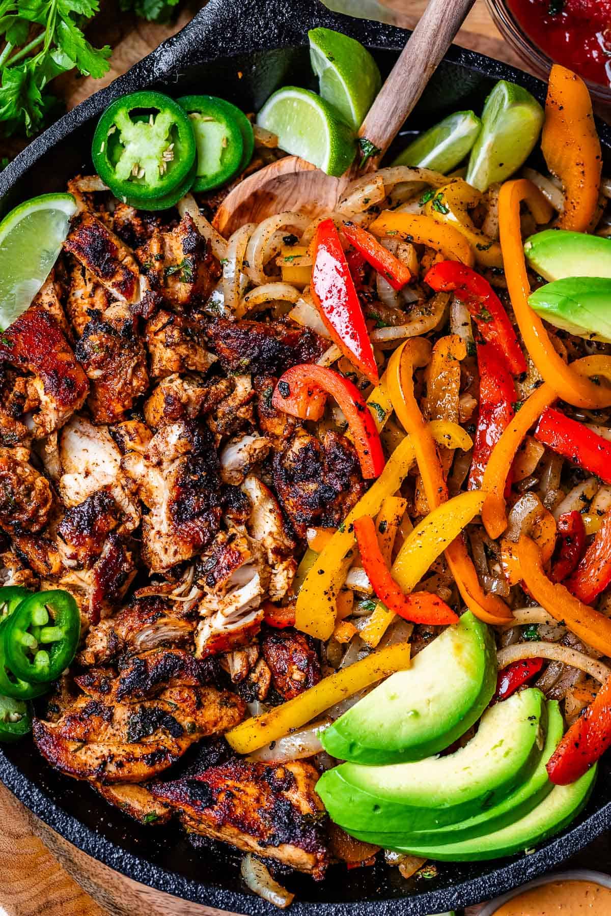 cast iron skillet filled with blackened chicken on one side and peppers and onions on the other.