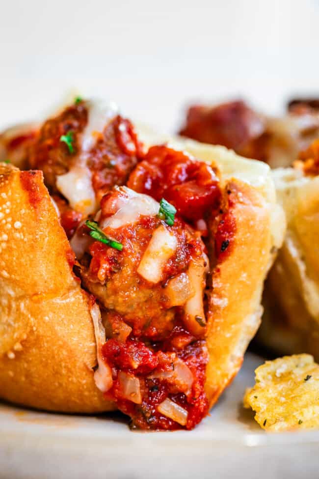 sideways view looking into the first bite of a meatball sub with all the sauce and cheese.