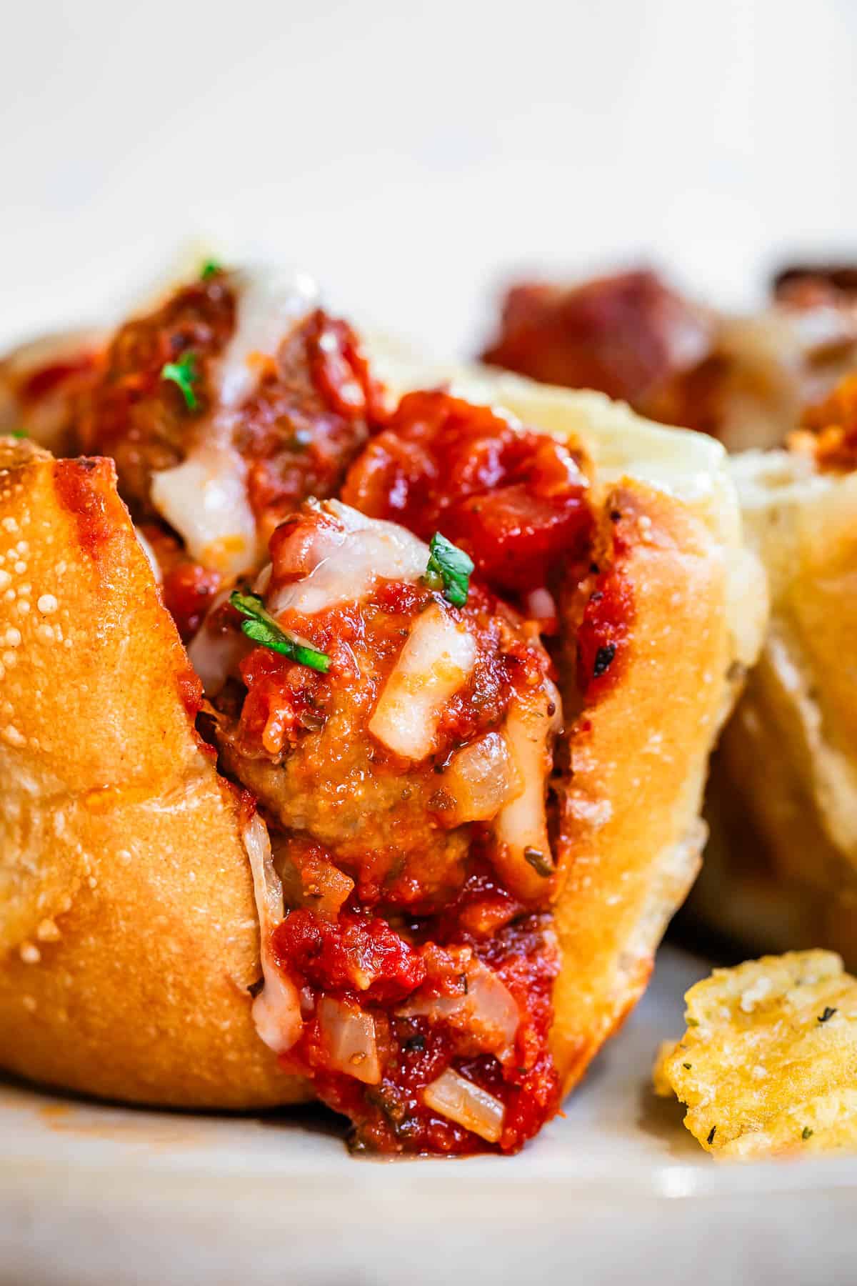 sideways view looking into the first bite of a meatball sub with all the sauce and cheese.