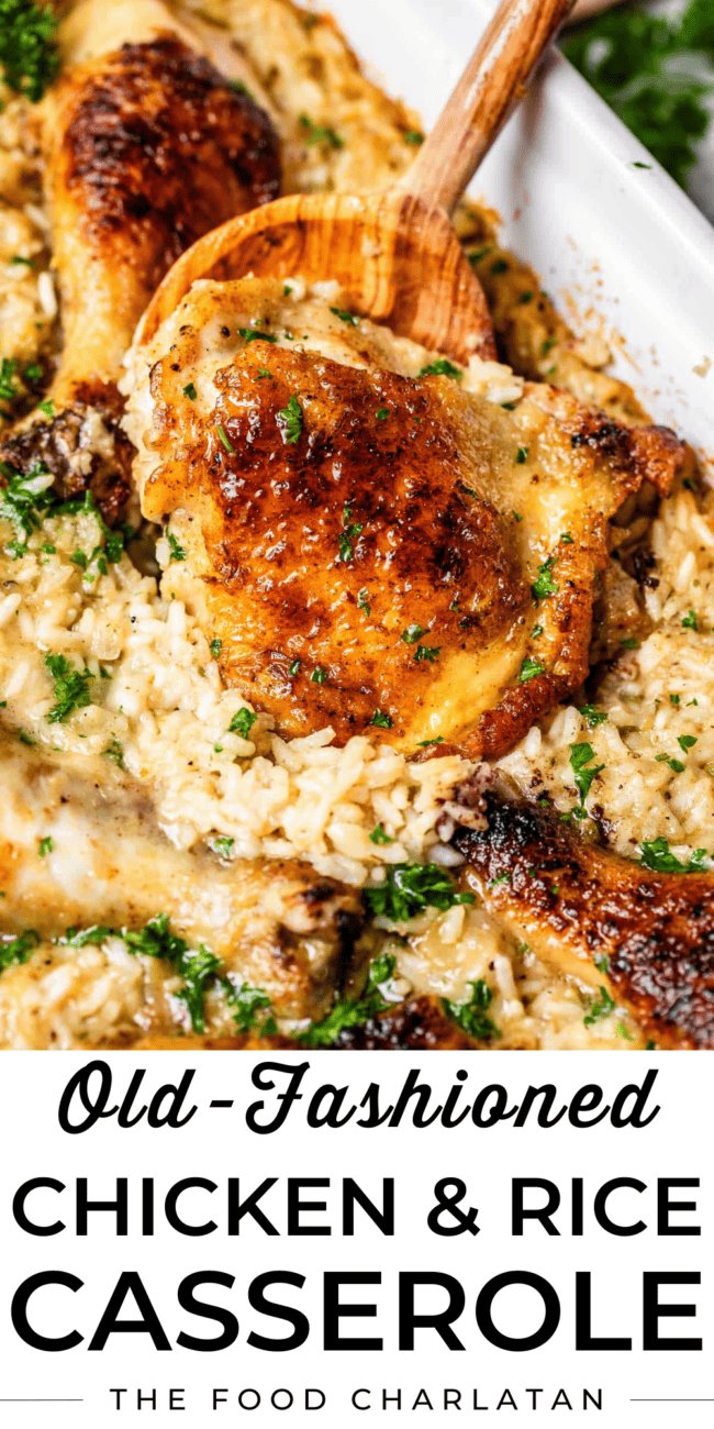wooden spoon holding up a browned chicken thigh in a casserole dish with rice.
