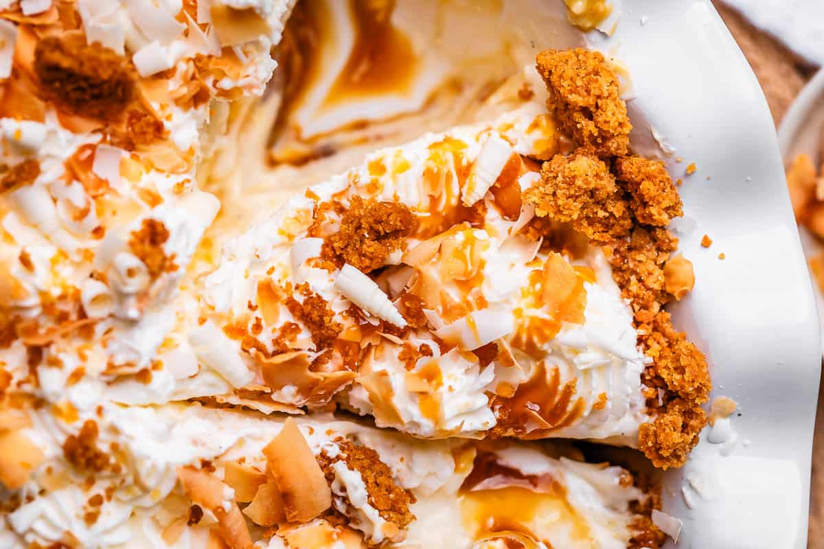 slice of easy coconut cream pie in a white pan and graham crust.