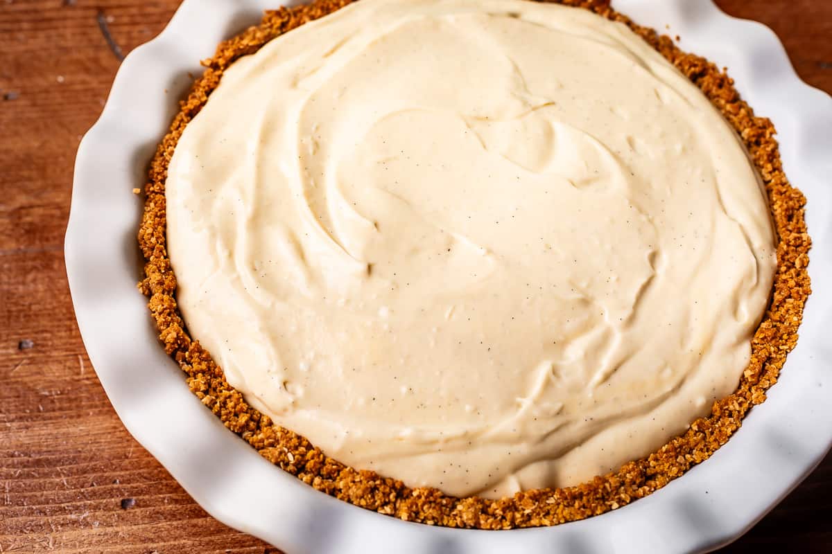 coconut filling spread evenly inside a crust in a ceramic pie plate.