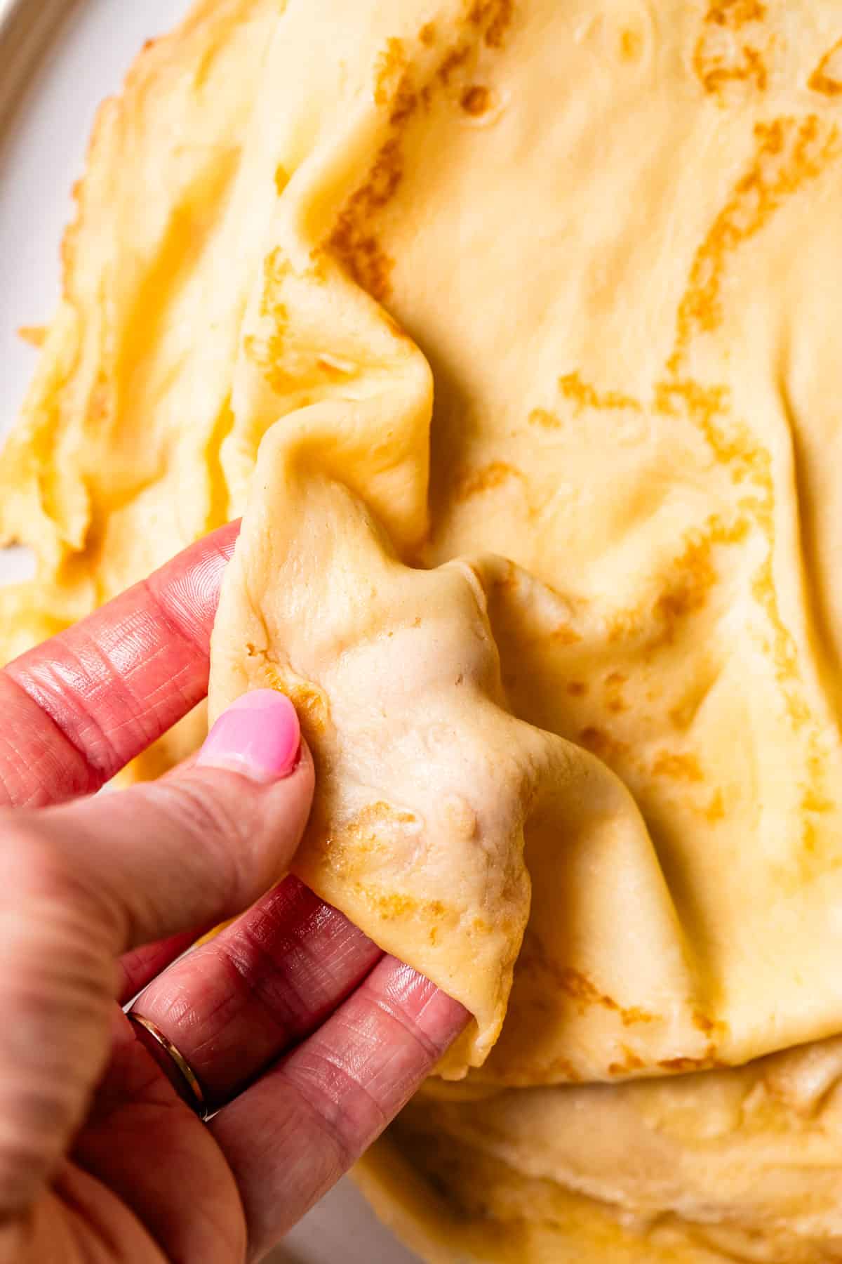 hand holding a crepe and showing a pliable and thin it is, without falling apart.