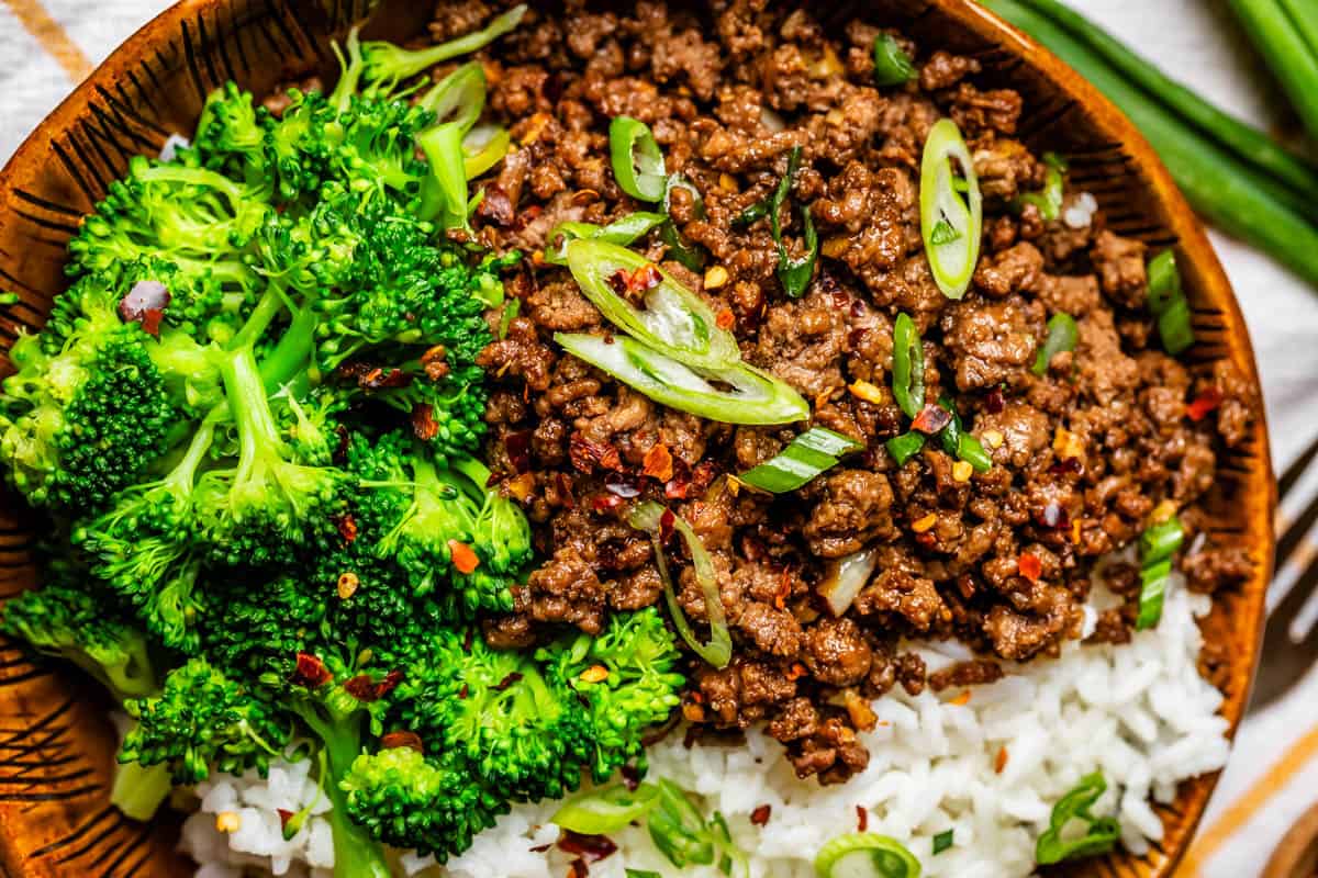 close up of cooked broccoli next to Korean beef topped with green onion.