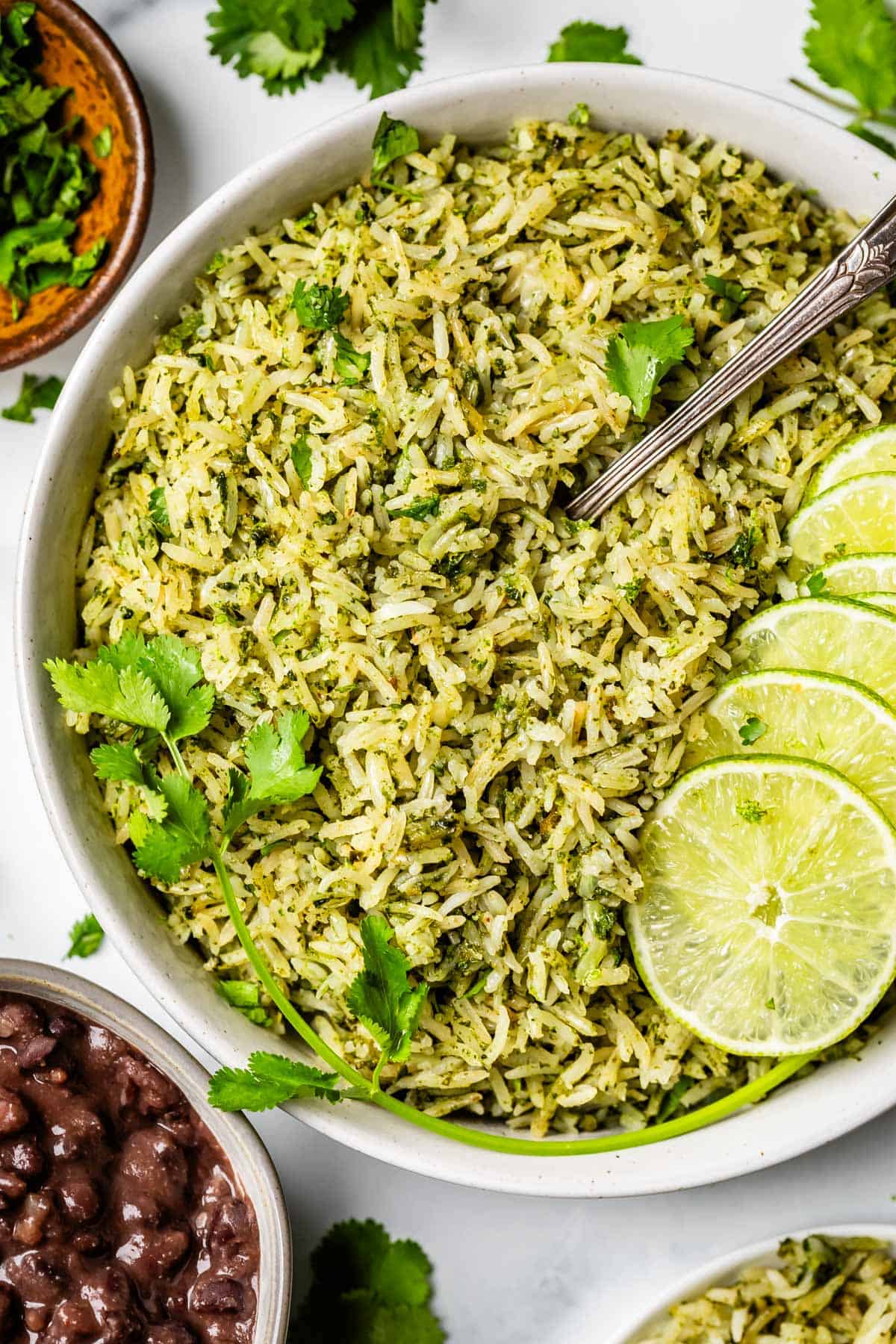 ceramic bowl filled to the brim with cilantro lime rice with a work and lime & cilantro garnish.