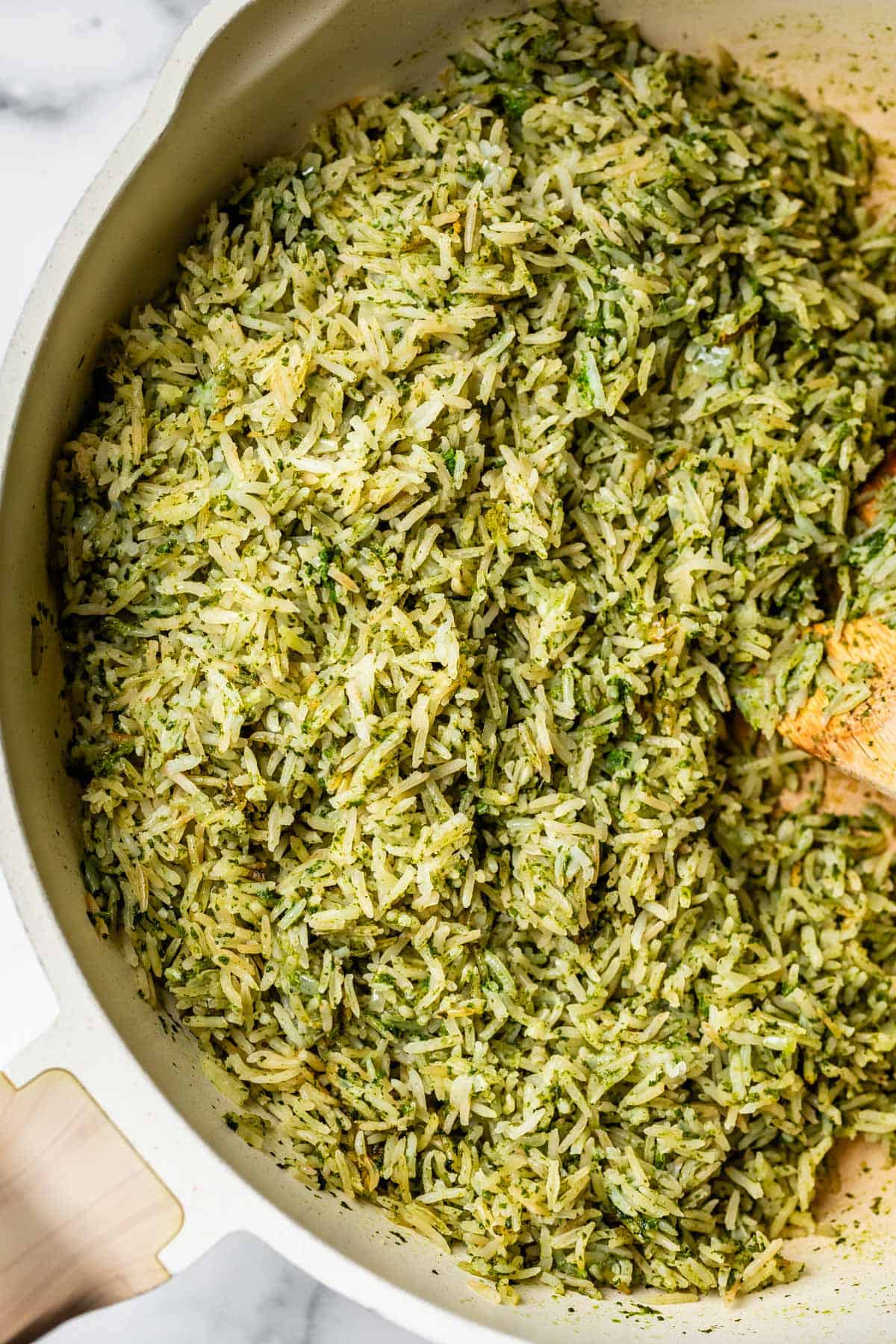 cooked and stirred cilantro lime rice in a cooking pot with a wooden spoon.