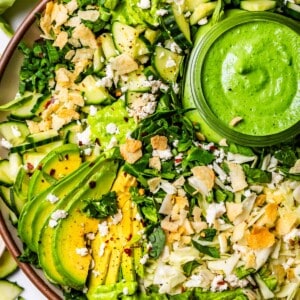 plate full of green goddess salad topped with chips, avocado, and extra dressing.