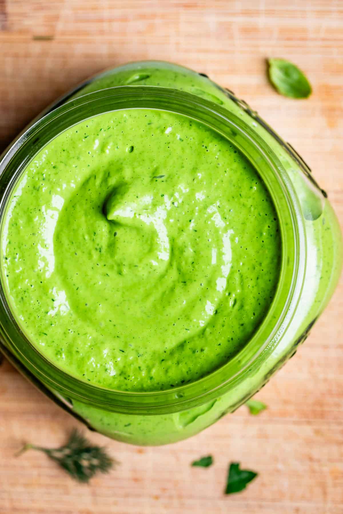 overhead shot of green goddess dressing swirled in a mason jar.