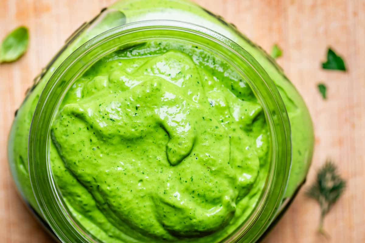 looking down at blended green goddess dressing in a glass mason jar.