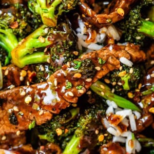 Close up of Chinese food beef and broccoli, with sauce and sesame seeds and rice.