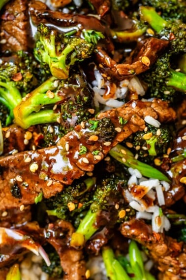 Close up of Chinese food beef and broccoli, with sauce and sesame seeds and rice.