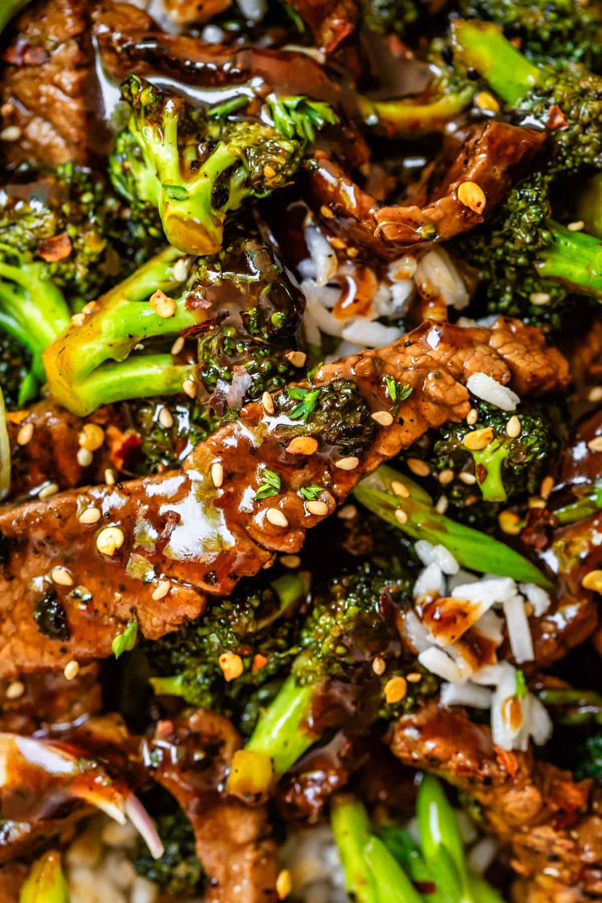 Close up of Chinese food beef and broccoli, with sauce and sesame seeds and rice.