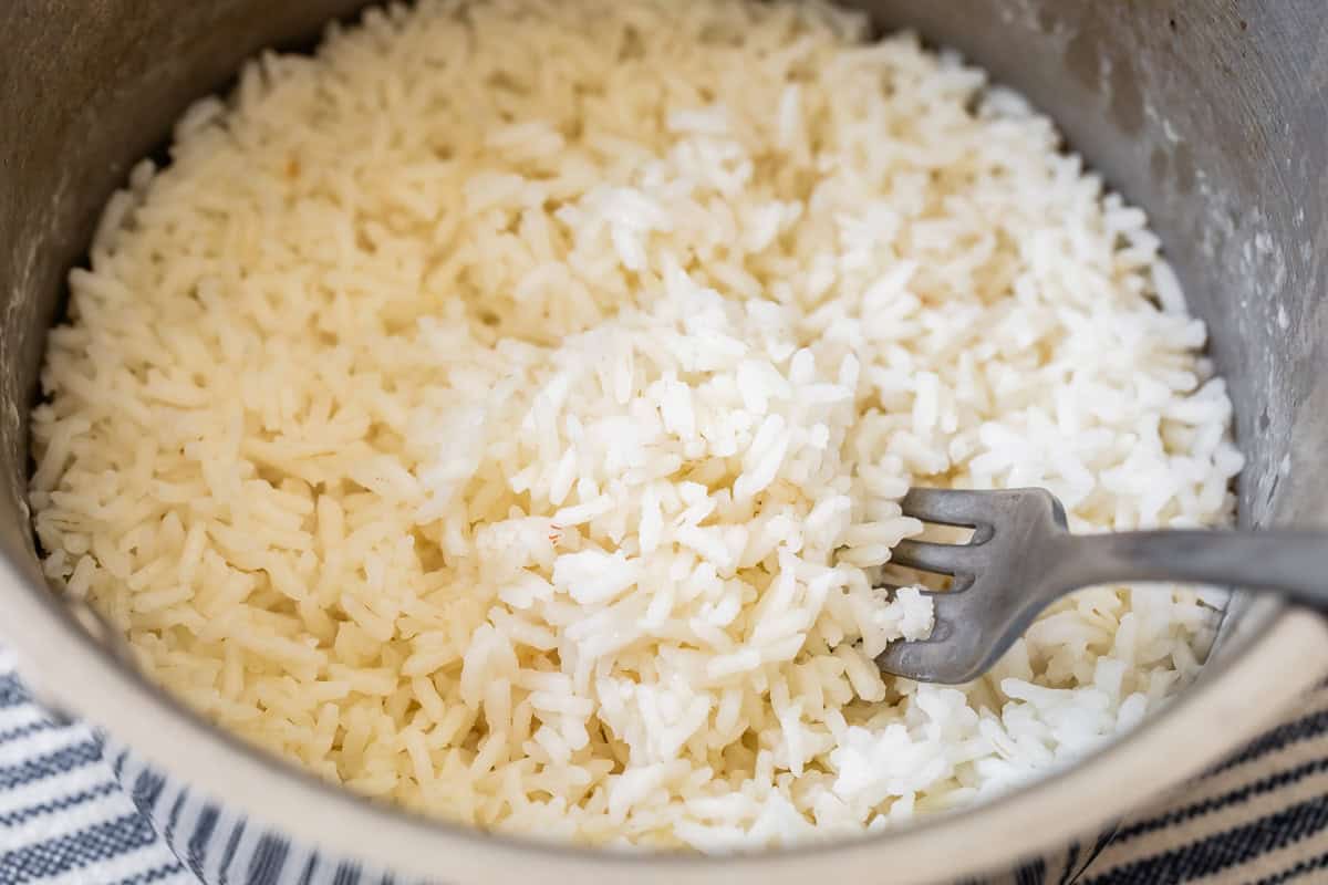 Fluffing cooked rice in a pot with a fork.