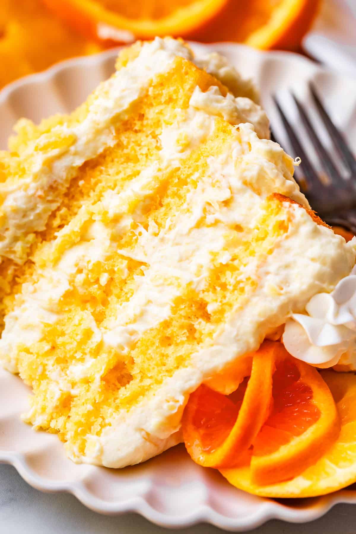 slice of sunshine cake showing all the layers on a ceramic plate with a metal fork.