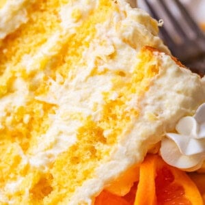 slice of four layers of yellow mandarin cake layered with pineapple whipped cream on a plate.